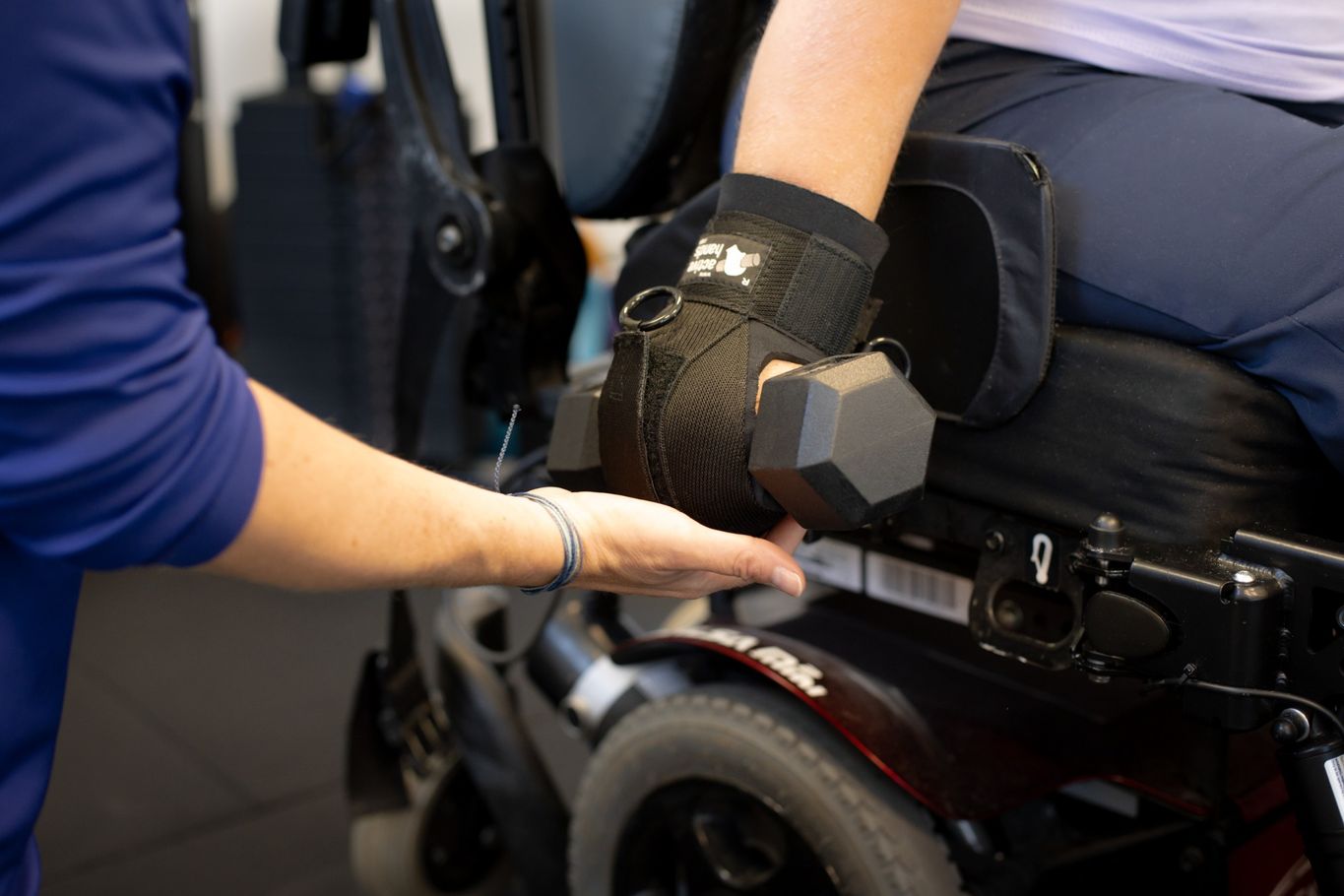 Close up image of an active hands gripping device on a hand with a dumbbell held securely