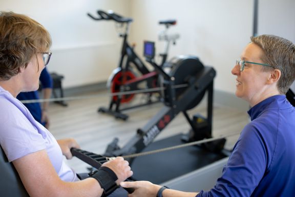 A client in an electric wheelchair using the rowing machine.