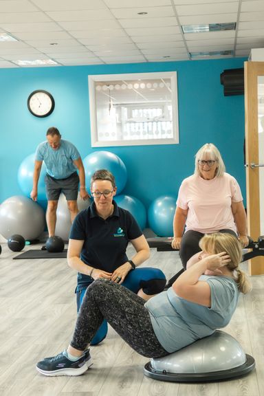 Group exercise class with 2 females and one male exercising and smiling.